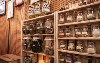 A shelf covered in labelled glass containers of herbs and other assorted sundries