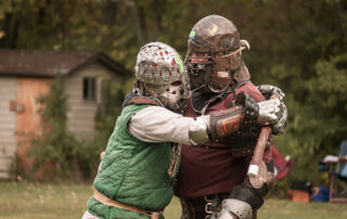 Sir Tristham in green gives Lord Grimmroth a hug