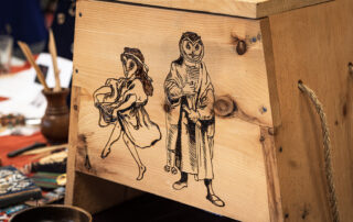A wooden chest decorated with wood burnings of two owl-headed figures